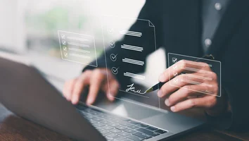 Hand einer Person, die mit einem Stift auf einem Laptop eine digitale Unterschrift auf einem virtuellen Dokument setzt