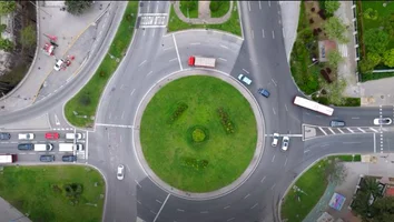 Luftaufnahme eines Kreisverkehrs mit mehreren Fahrzeugen und umliegenden Straßen und Grünflächen