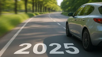 Auto fährt auf einer von Bäumen gesäumten Landstraße mit der Zahl 2025 auf der Fahrbahn