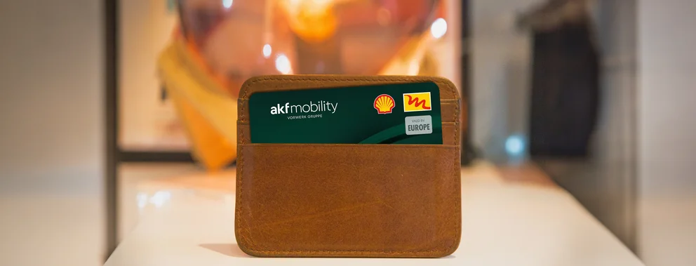 Braune Ledertasche mit einer Tankkarte von akf mobility und Shell Europe stehend auf weißer Oberfläche